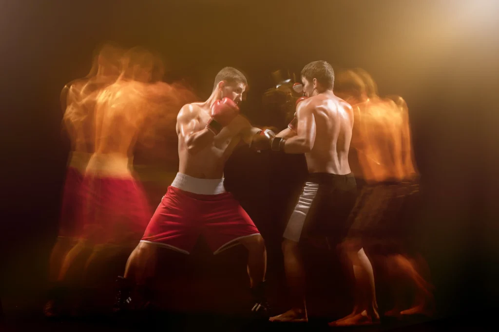 the two male boxers boxing in a dark studio